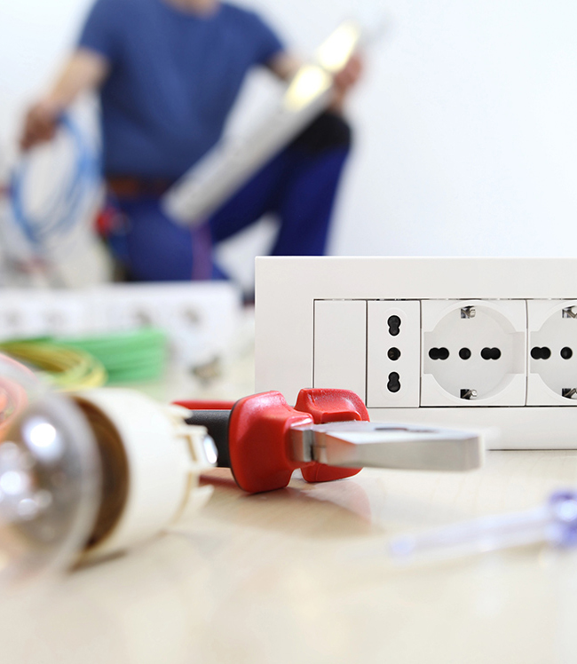 Electrician wearing safety gloves and helmet working on a circuit breaker panel