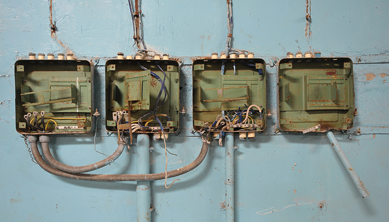Residential Electrician 3 Old rusted electrical junction boxes with exposed wiring on a wall